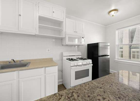 A kitchen with white cabinets and a granite countertop at Pleasant Oak Apartments, Oak Park, IL, 60302
