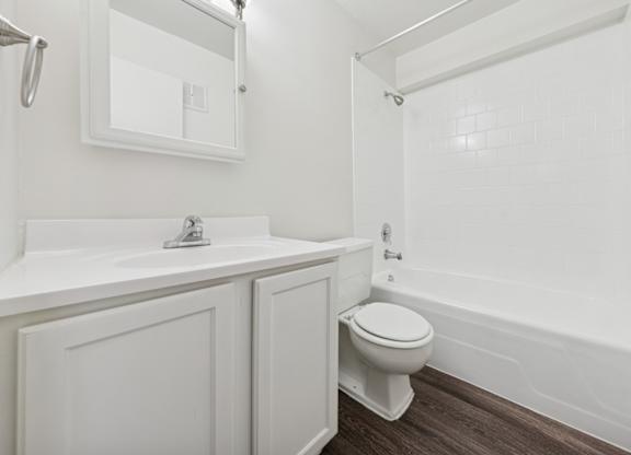 A white bathroom with a toilet, sink, and mirror.