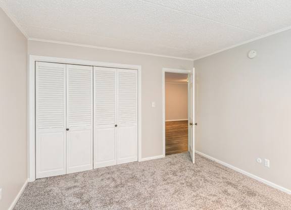A room with a white door and a carpeted floor.