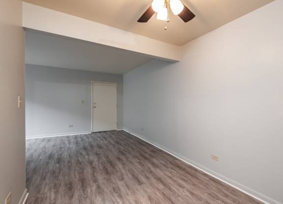 A room with a white door and a brown floor.