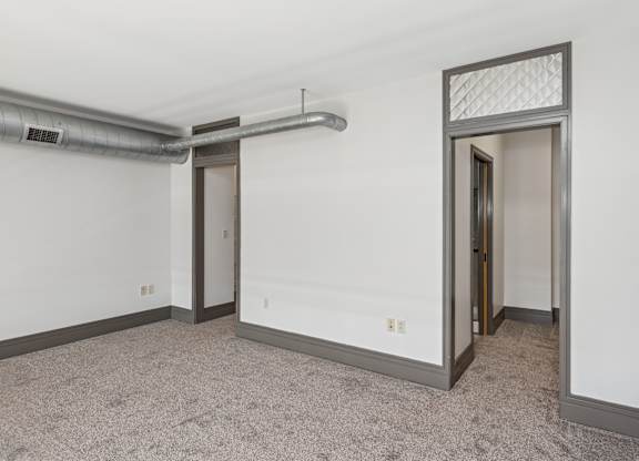 A room with a carpeted floor and a doorway leading to another room.