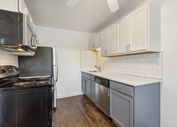 a kitchen with white cabinets and black appliances at The Hinsdale, Hinsdale, Illinois