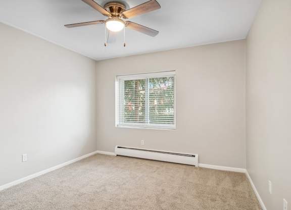 A room with a ceiling fan and a window with blinds.