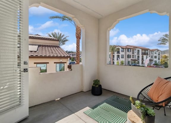 a balcony with a chair and a view of a palm tree at Arrive Temecula