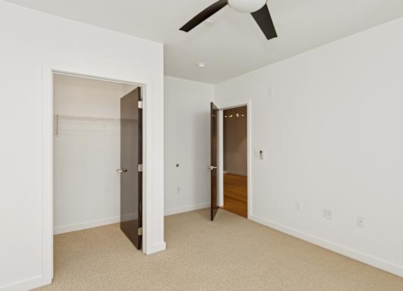 A room with a ceiling fan and two doors.