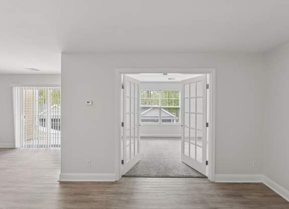 A room with a white door and a grey carpet.