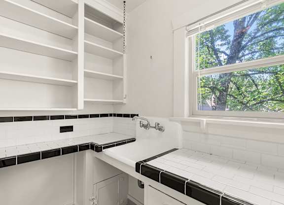 A white kitchen with black and white tiles.