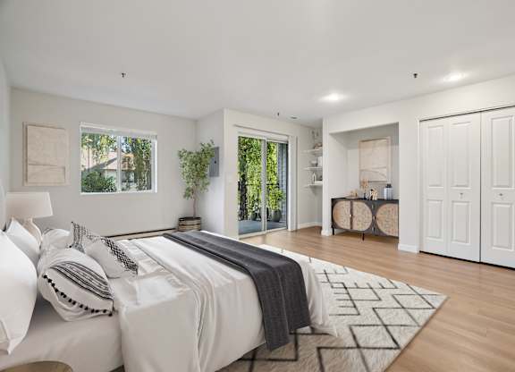 A bedroom with a large bed and a view of trees through the window.
