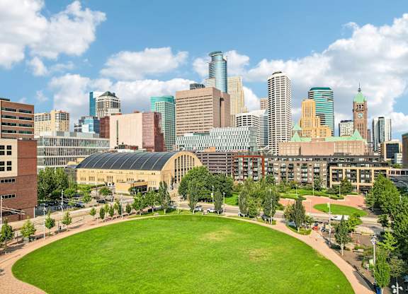 A city skyline with a green field in the foreground.