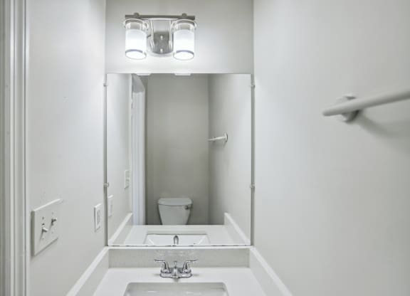 A white bathroom with a sink and mirror.