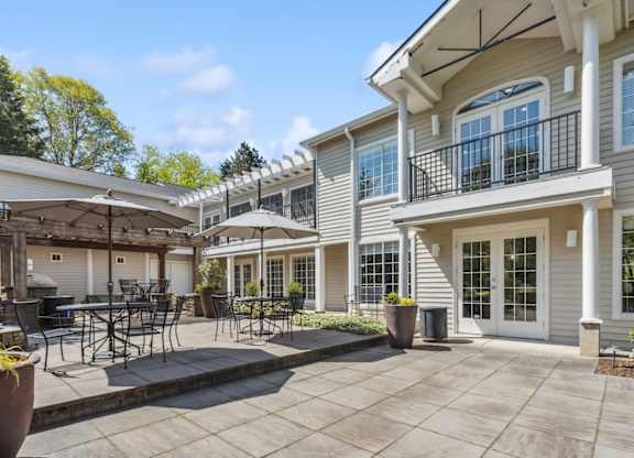 A patio area with a table and chairs is in front of a two-story apartments