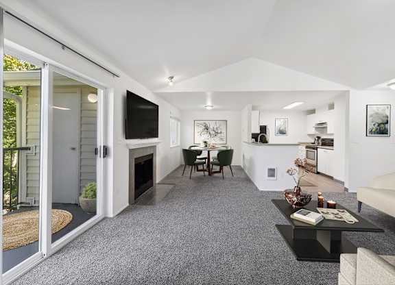 A modern living room with a grey carpet and white walls.