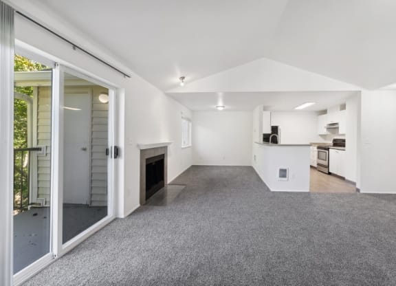 a spacious living room view with carpet flooring, a view of the kitchen, and a fireplace at Murrayhill Park, Beaverton Oregon
