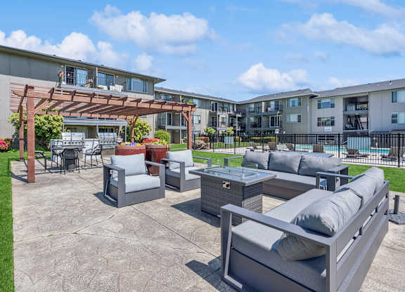 A patio area with grey furniture and a pool in the background.