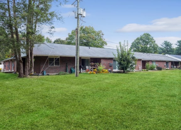 a view of the front of a brick house with a green yard