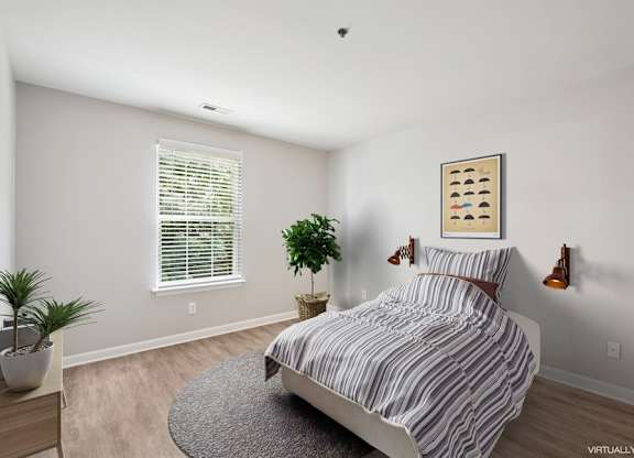 A bedroom with a bed, a plant, and a picture on the wall.
