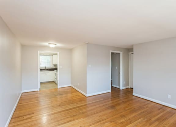 an empty living room with wood floors and white walls