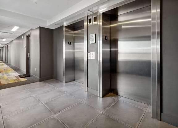 a row of elevators in a hallway with doors at The Rowe, Grand Rapids, 49503