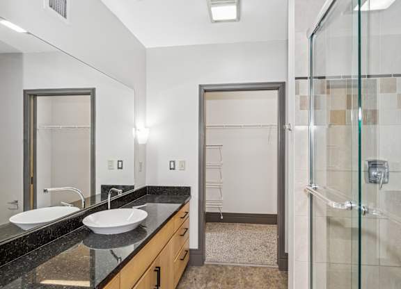 A bathroom with a sink, mirror, and shower.