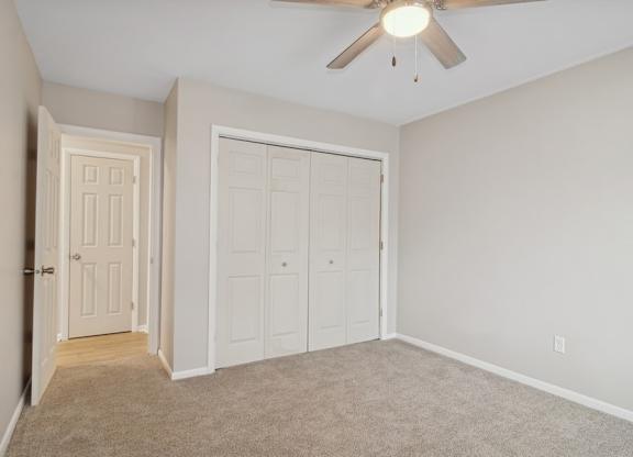A room with a ceiling fan and two doors.