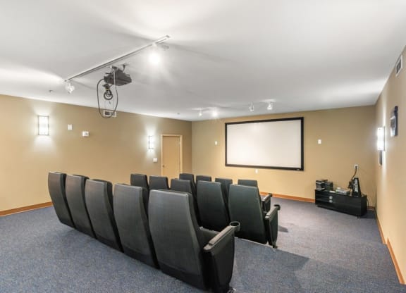 a theater room with a projector screen and chairs