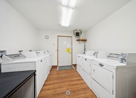 A white kitchen with a black counter top and wooden floors.
