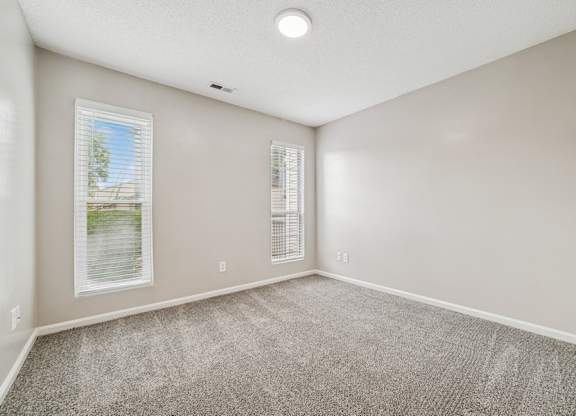 A bedroom with a window and a carpeted floor.