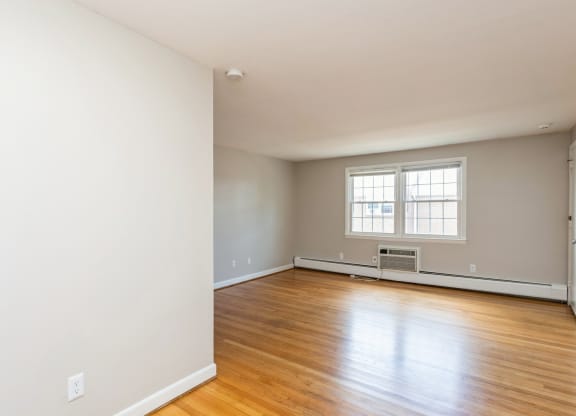 the living room of an empty house with wood floors and a window