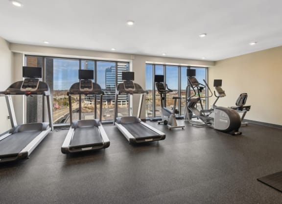 a gym with cardio equipment and windows with a view of the city at The Rowe, Grand Rapids, 49503