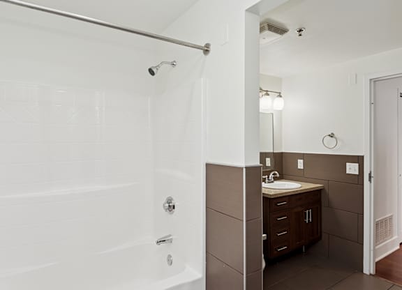 A white tiled bathroom with a sink and mirror.