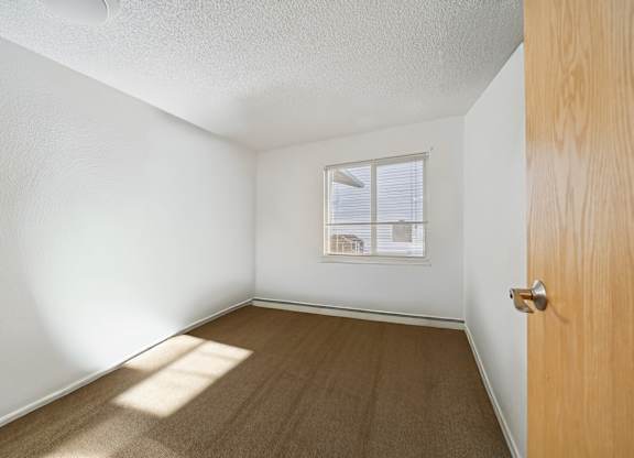A room with a wooden door and a window with blinds.