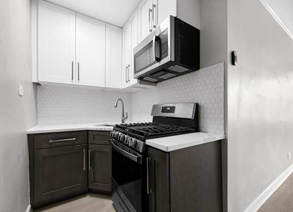 A kitchen with a black stove top oven and black microwave above it at Pleasant Oak Apartments, Illinois, 60302