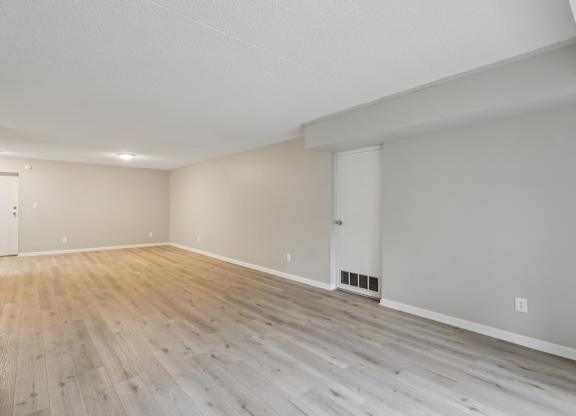 A room with light wood flooring and white walls.