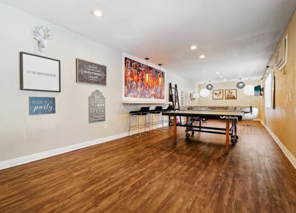 a game room with a ping pong table and paintings on the wall