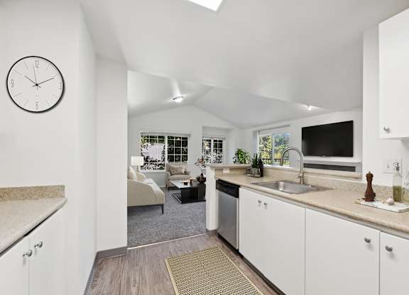 A kitchen with white cabinets and a clock on the wall.