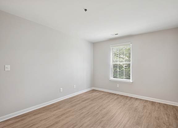 A room with a window and wooden flooring.