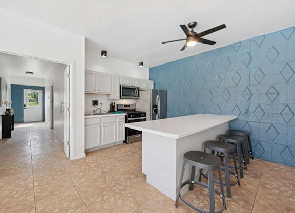 A kitchen with a blue wall and a bar area.