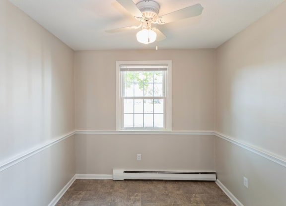 Empty carpeted room with ceiling fan and window