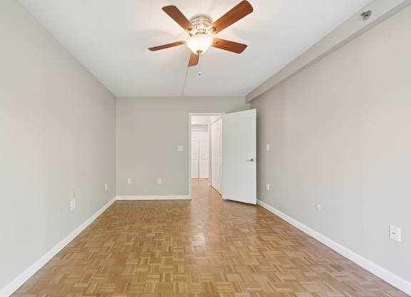 A room with a ceiling fan and wooden flooring.