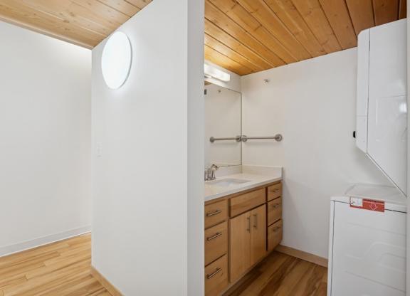 A small bathroom with a wooden floor and white walls.