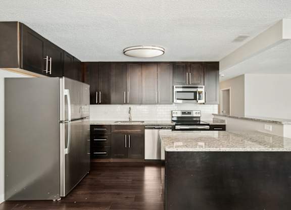 A modern kitchen with a refrigerator, microwave, and oven.