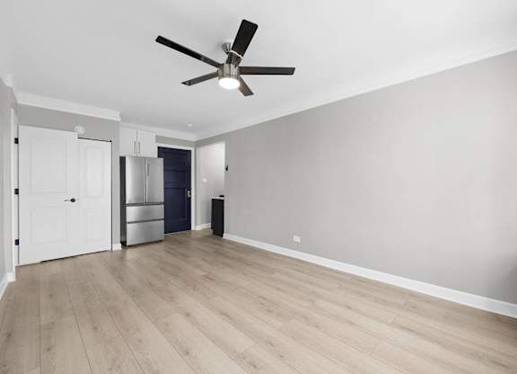 A room with a ceiling fan and light, hardwood floors, and a white door at Pleasant Oak Apartments, Illinois, 60302