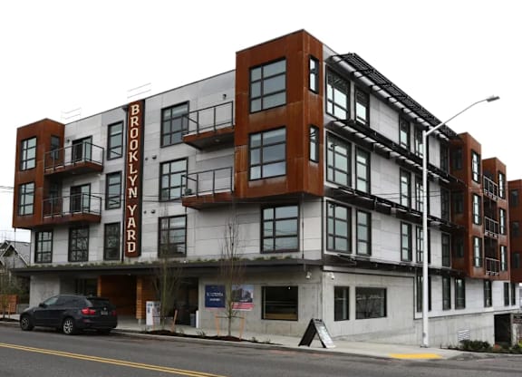 Modern mixed material building exterior with street view at Brooklyn Yard Apartments, Portland, OR 97202