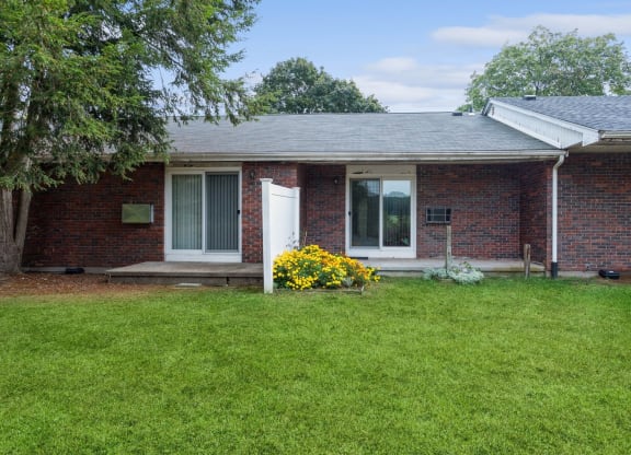 the front of a brick house with a lawn and a white door