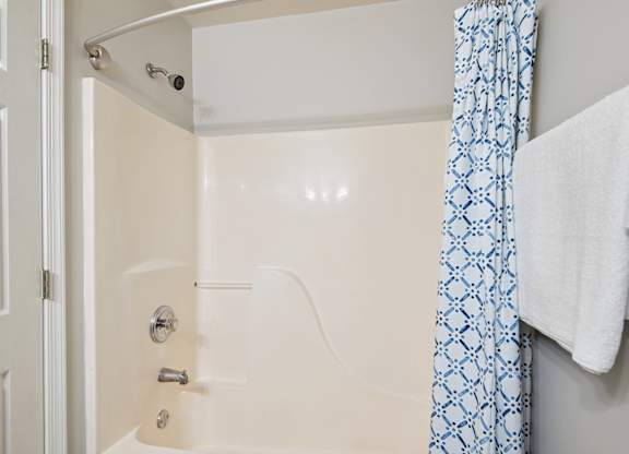 A white bathroom with a blue and white shower curtain.