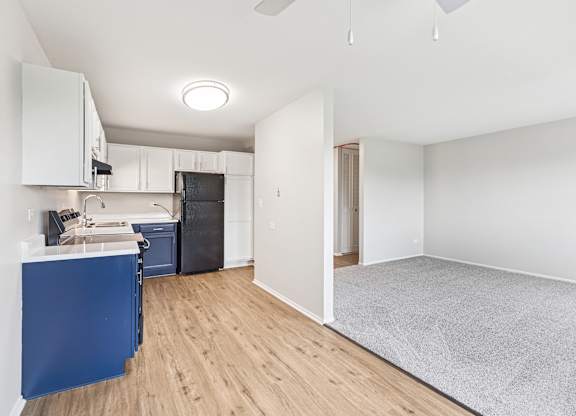 A kitchen with white cabinets and a wooden floor.