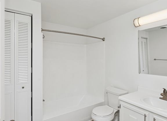 A white bathroom with a toilet, sink, and shower.