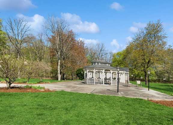 A gazebo is surrounded by a grassy area and trees.