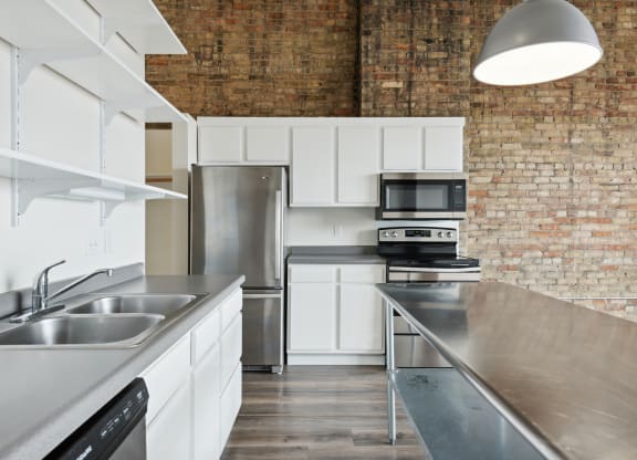 a kitchen with stainless steel countertops and a brick wallat Gaar Scott Historic Lofts, Minneapolis