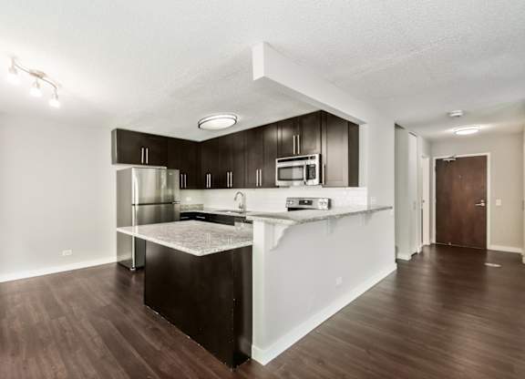 A kitchen with dark wood floors and white walls.